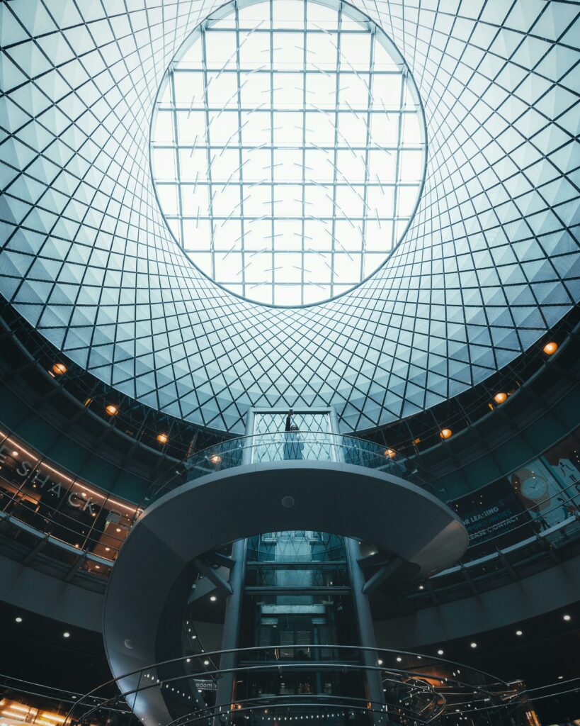 Modern circular glass ceiling with a spiral staircase in a futuristic building interior.